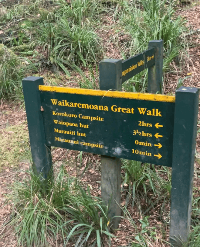 photo of a green and yellow DOC sign listing locations and walk times 