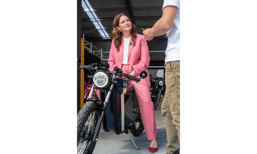 A photograph of Finance Minister Nicola Willis in a pink suit, sitting on a dirt bike.