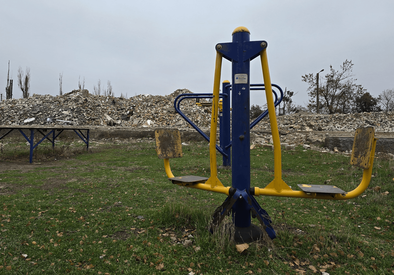 An empty playground in front of a pile of rubble