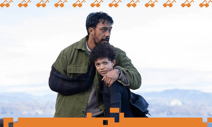 In a scene from TV drama Secret at Red Rocks, A man wearing a green jacket hugs his son tightly as they stand on a beach and look into the distance