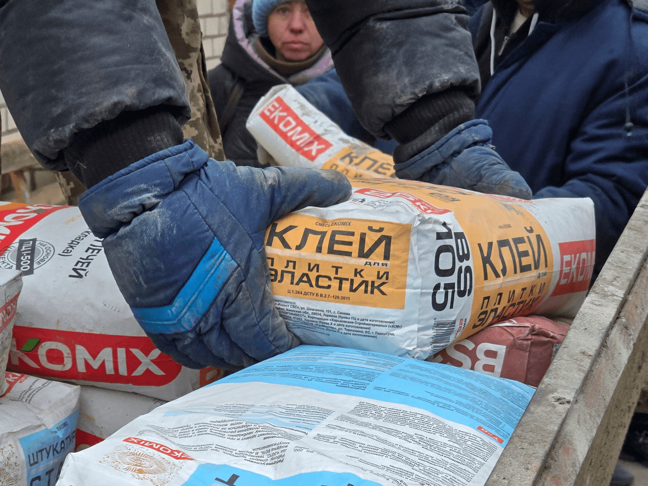 A close up of gloved hands picking up a bag of concrete