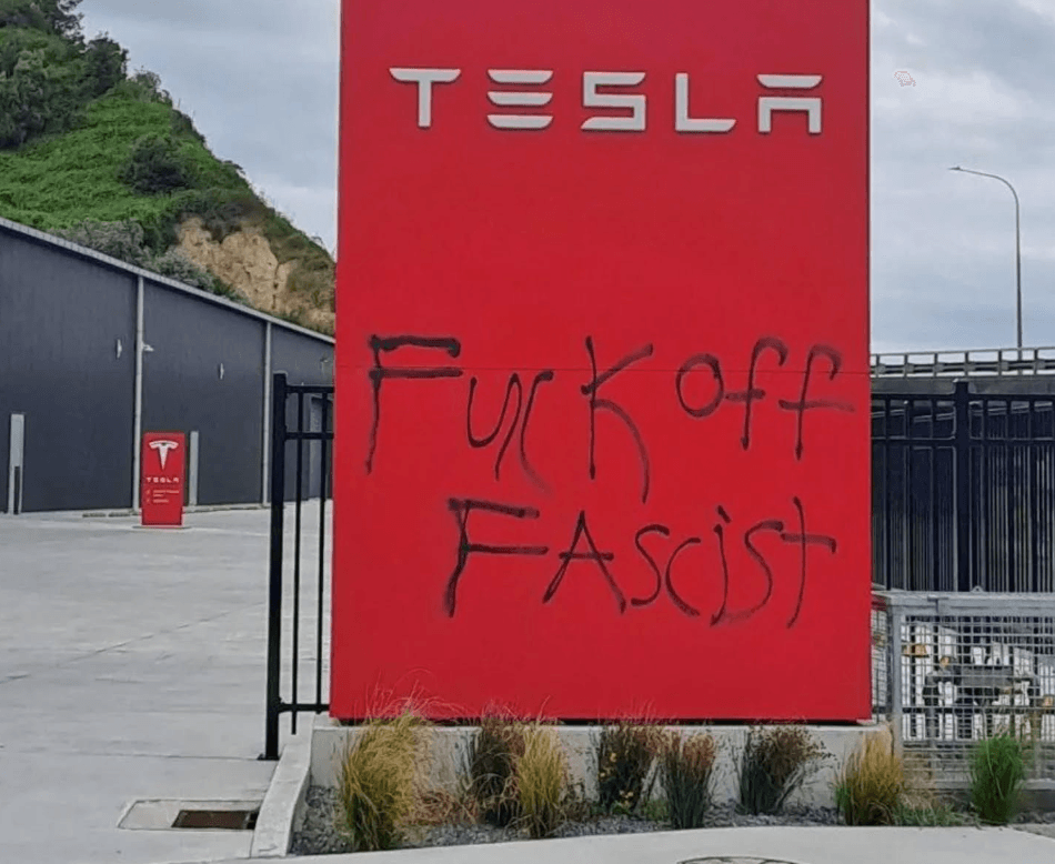 ret tesla signage with 'fuck off fascist' spray painted on in black