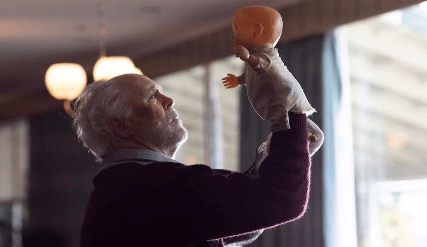 John Lithgow lifts up a doll puppet high into the air