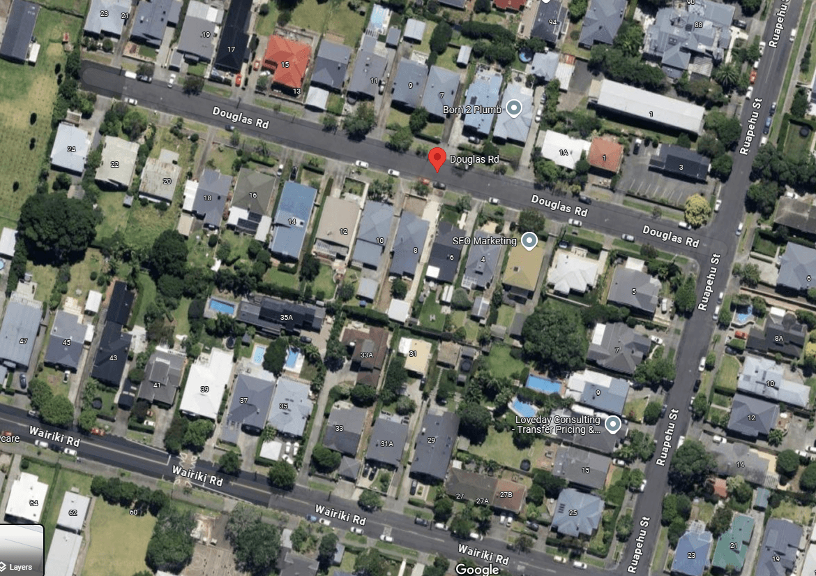 Aerial view of a suburban neighborhood with tree-lined streets. Houses with yards are arranged along Douglas Rd and Wairiki Rd. The roads intersect with Ruawai Rd. Pinned locations and labels are visible on the map.