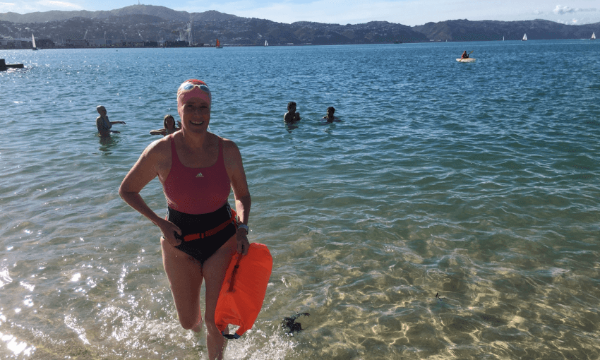 A photograph of Kate Camp walking out of the sea, smiling. 
