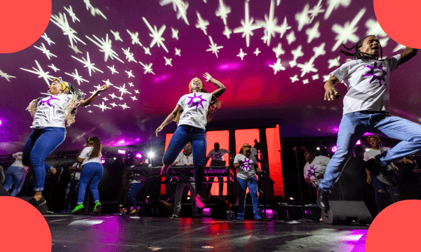 a group of men leapin in the air with white tshirts and blue jeans and shining projection on the ceiling