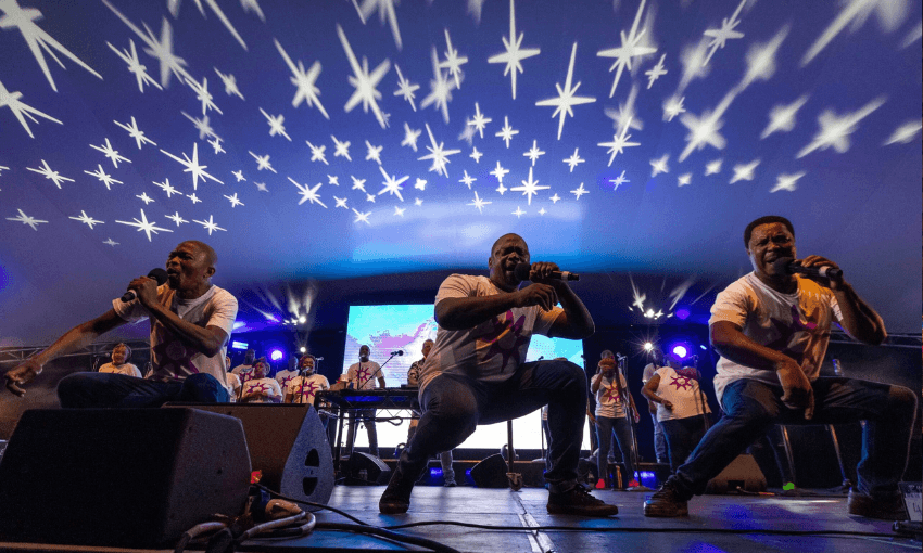 snazzy projects bracket a blue toned photo of three black men crouching as they sing into the microphone with more singers in the back