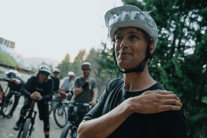 ben hildred rests his hand on his chest with a bemused look on his face, with other cyclists in the background