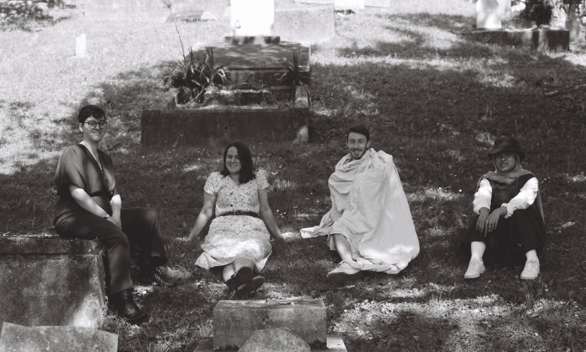A black and white film photograph of four people sitting on grass.