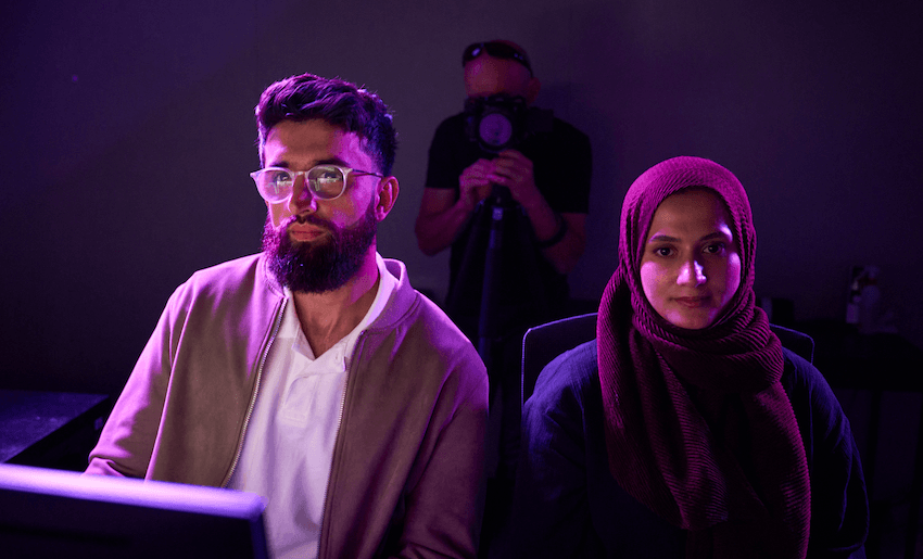 Bariz Shah and Saba Afrasyabi sit in the purple glow of a computer screen