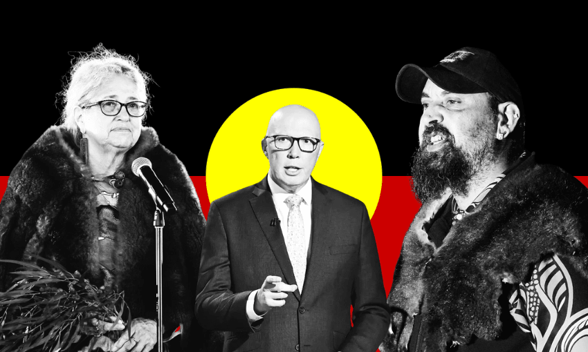 Three people stand in front of the Australian Aboriginal flag: a woman with a microphone on the left, a man in a suit in the centre, and a man wearing a cap and cloak on the right.