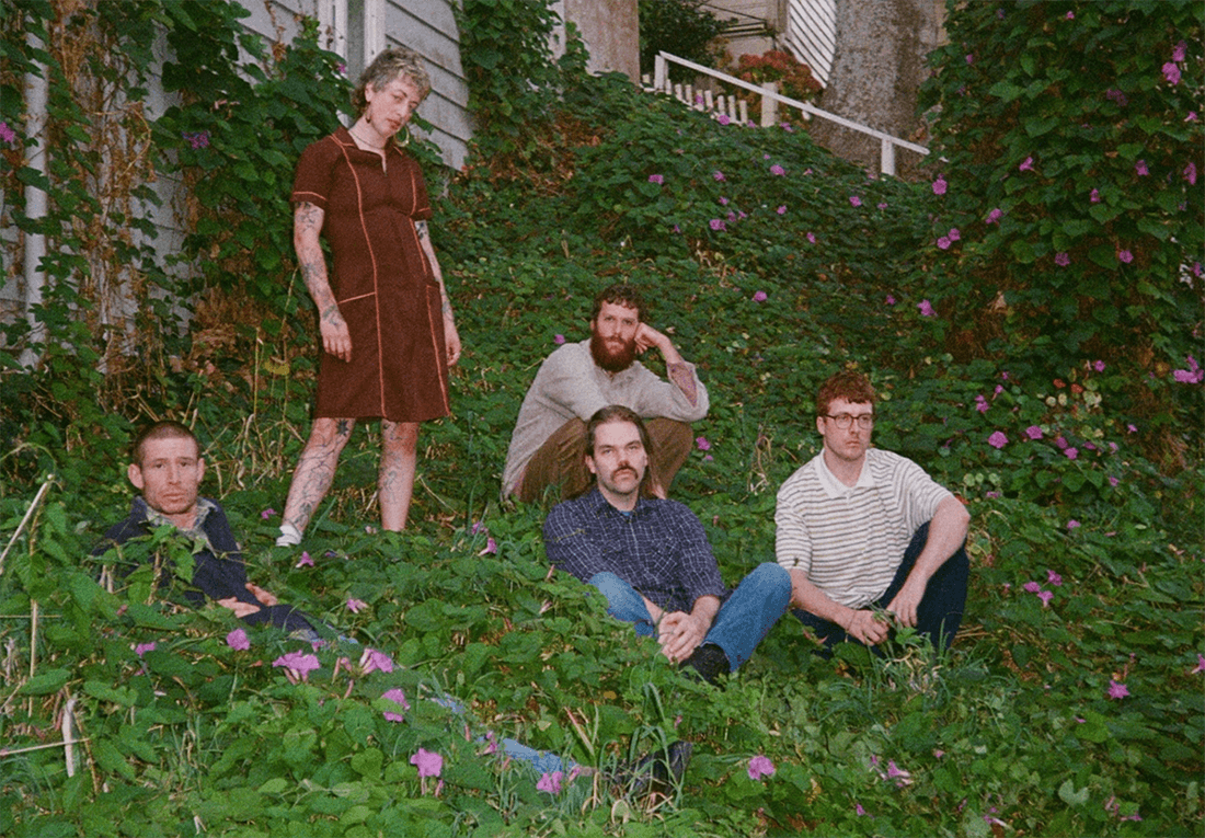 a group of five indie musicians standing in vines