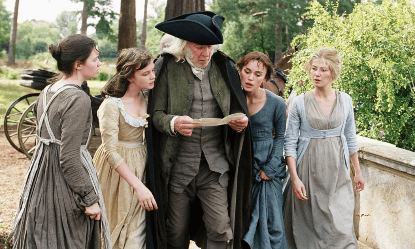 Donald Sutherland as Mr Bennet is reading a letter and is surrounded by his daughters, two on either side. They are all outside, walking. 