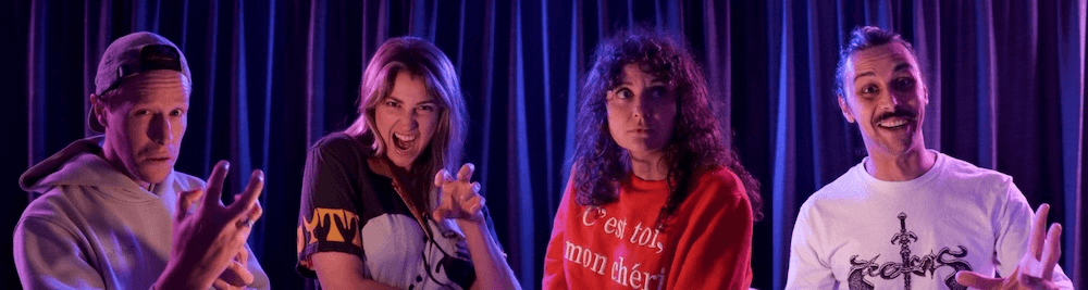 four people stand in front of a black velvet curtain, smiling