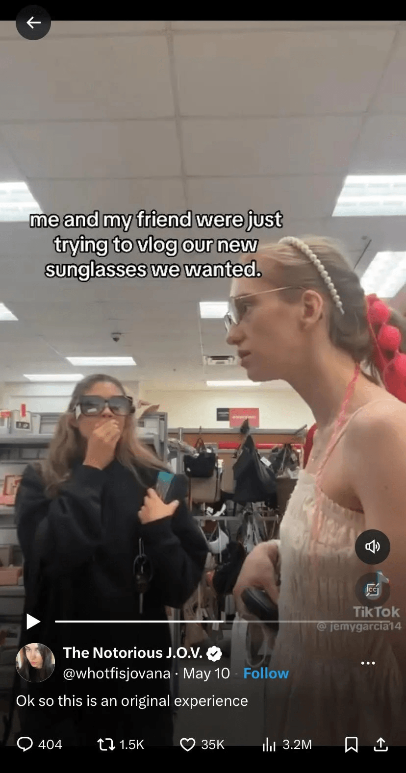 Two young women stand in a store; one is holding her hand to her mouth, looking surprised, while the other in a dress and sunglasses speaks. Caption reads: "me and my friend were just trying to vlog our new sunglasses we wanted.