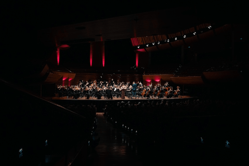 a dark concert hall with a lot of interesting instrument on an illuminated stage