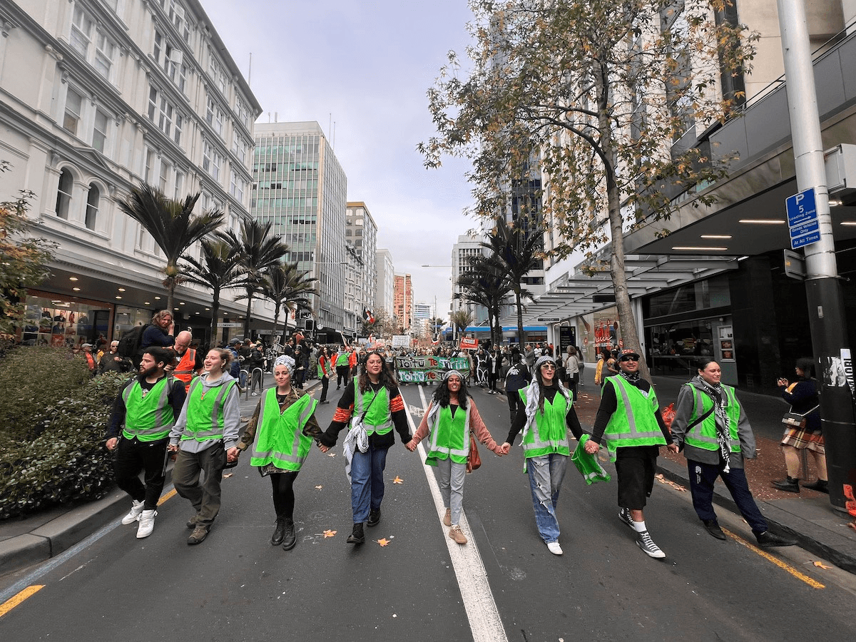 poeple in fluro green vests holding hands and walking down urban street
