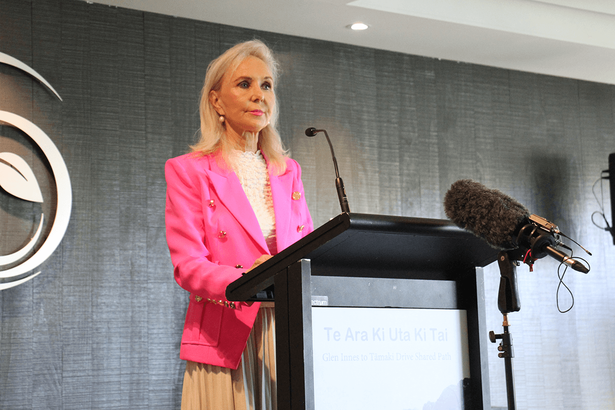 Desley simpson in pink standing at a lecturn
