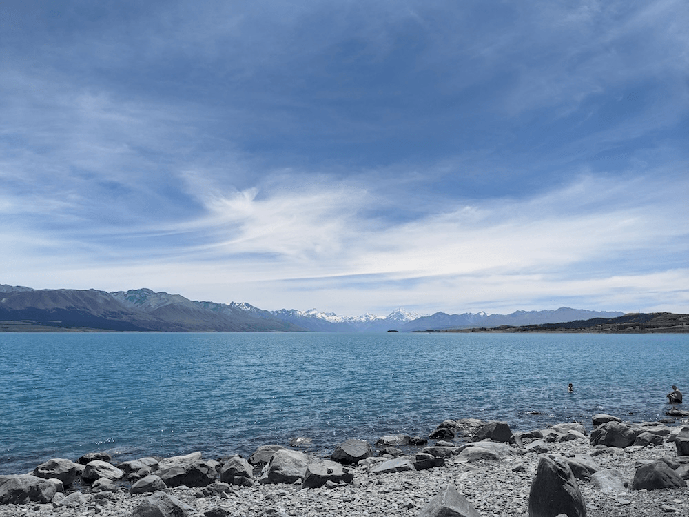 a blue glacier fed lake with aoraki a pointy glimmer at the end of the valley