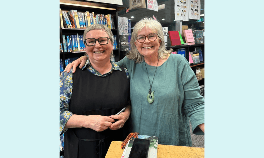 A photograph of two middle aged women smiling with bookshelves behind them. 