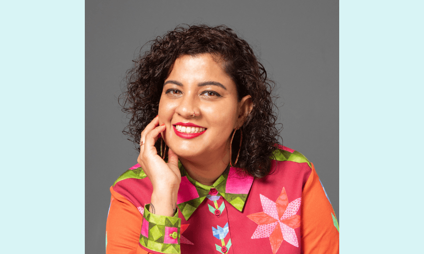 a brown woman wearing a colouful pink orange and green patchworked shirt, with curly black hear and a smile