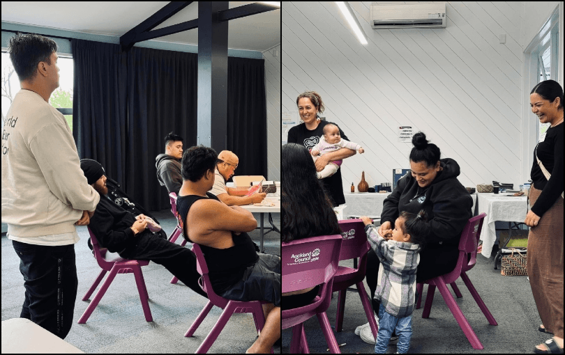 A group of people sit and chat in a community room. On the left, some are seated while others stand and listen. On the right, a woman holds a baby as another child interacts with seated adults, creating a warm, social atmosphere.