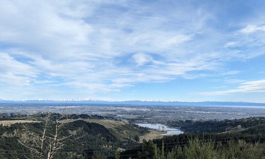 a big blue sky and a small aptch of water visible at the base of the hills below