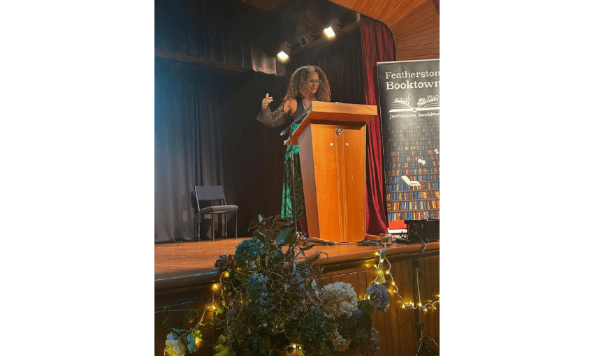 A photo of Selina Tusitala Marsh, a Pasifika woman, standing at a lectern and speaking.