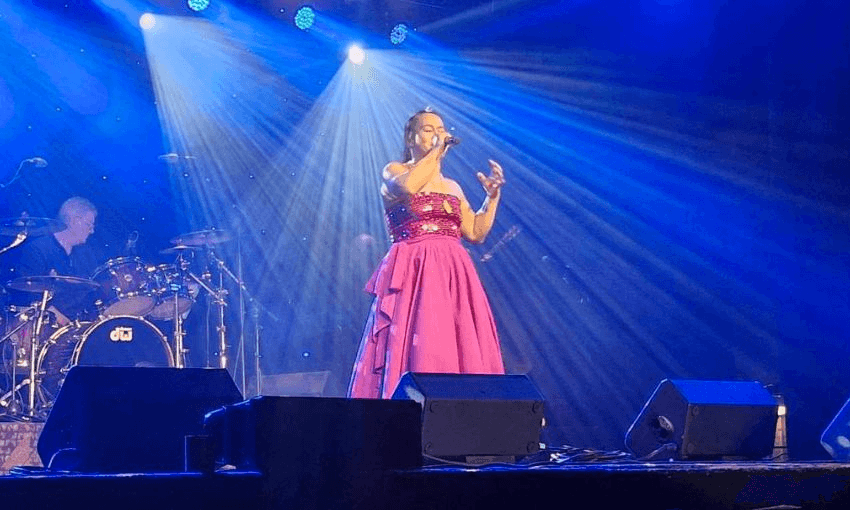 Amy Maynard performing in the 2025 Gold Guitar circuit in a pink dress.