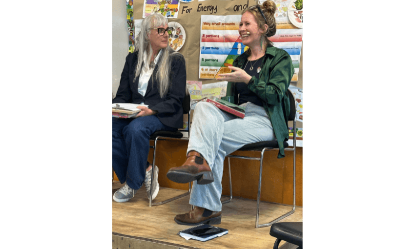 Two women sitting on chairs talking to each other. 
