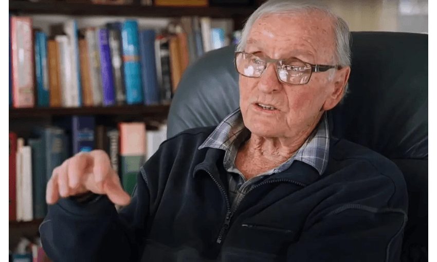 An elderly man is sitting in an armchair, talking.