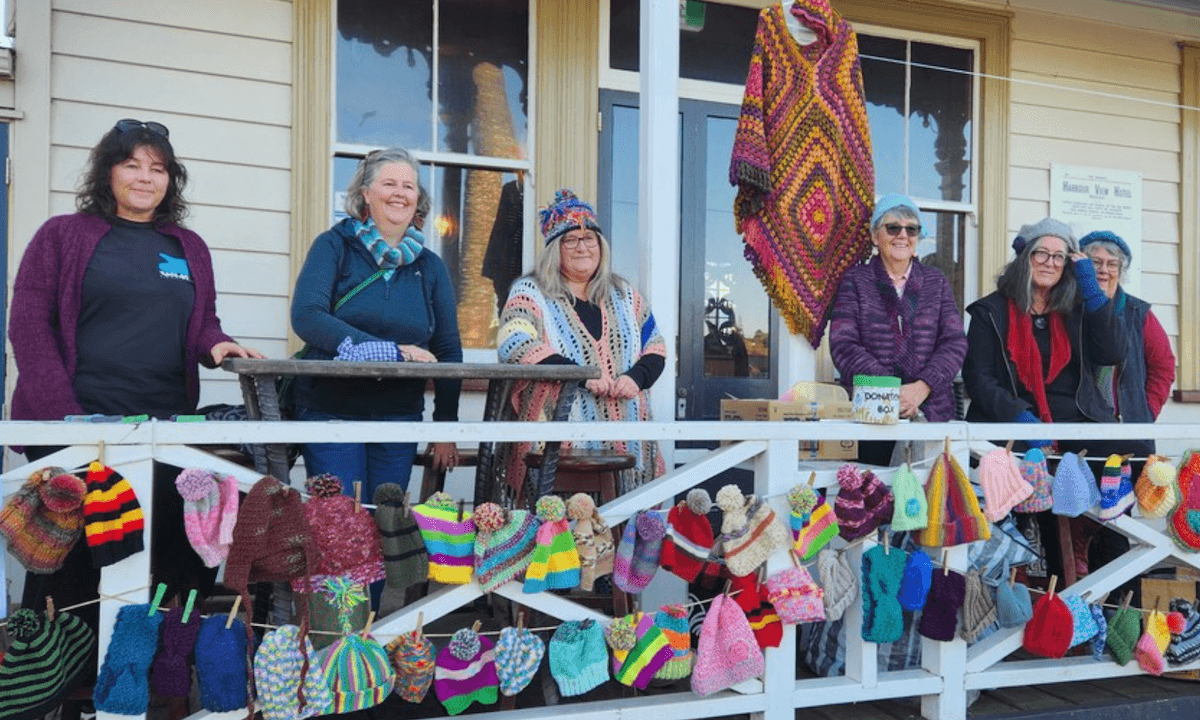 women on a porch with loads of handknitted beanies
