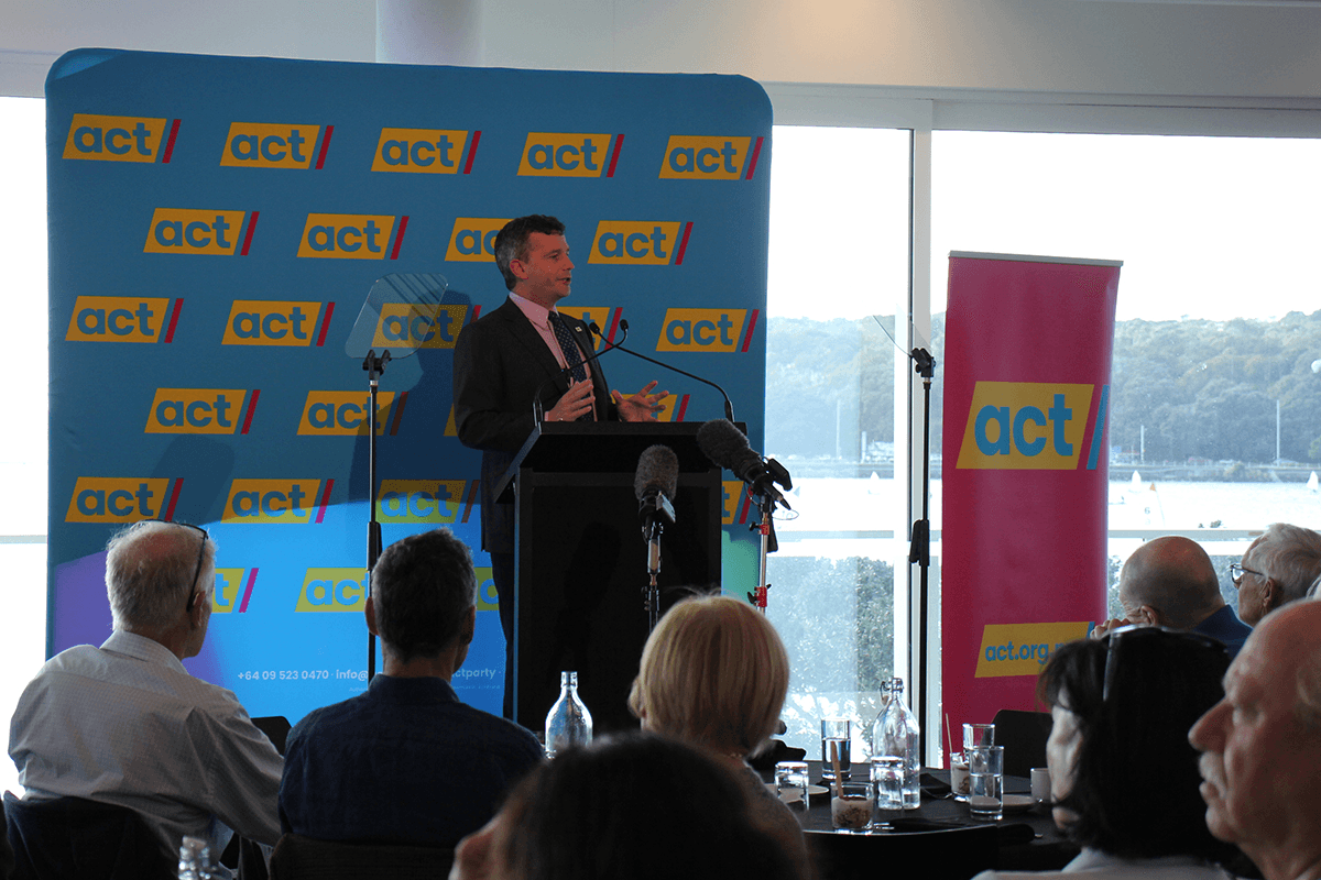 david seymour in front of an act party banner