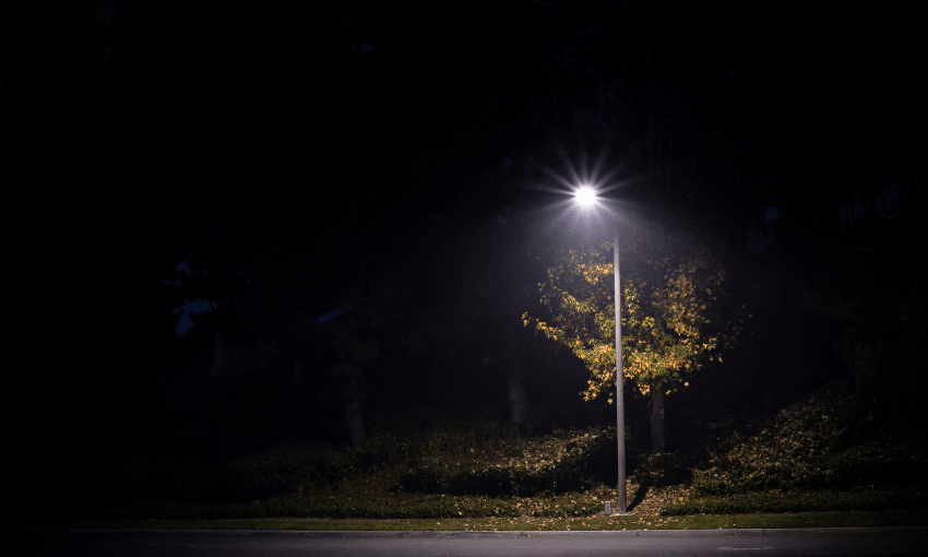 a dark street with lots of shadows and a single streetlight