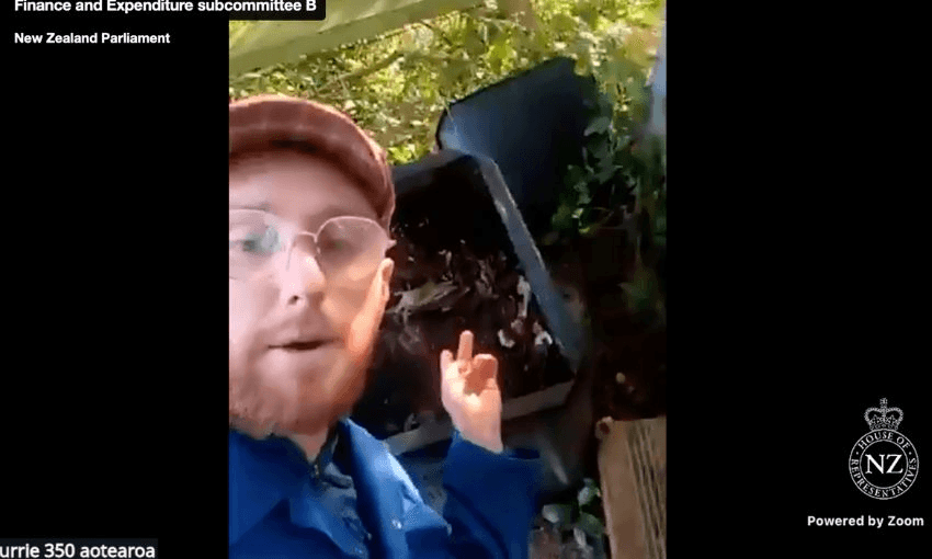 Adam Currie stands in front of, and points to, a compost heap.