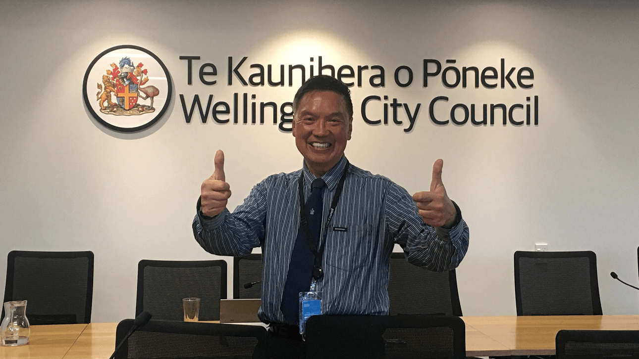 A man standing in a board room with two thumbs up