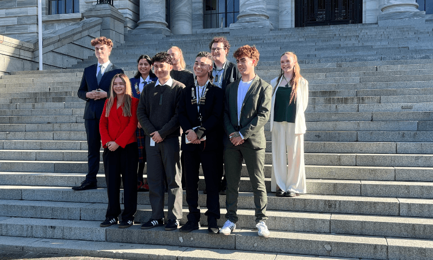 Nine Youth MPs pose for photos outside the parliament steps.