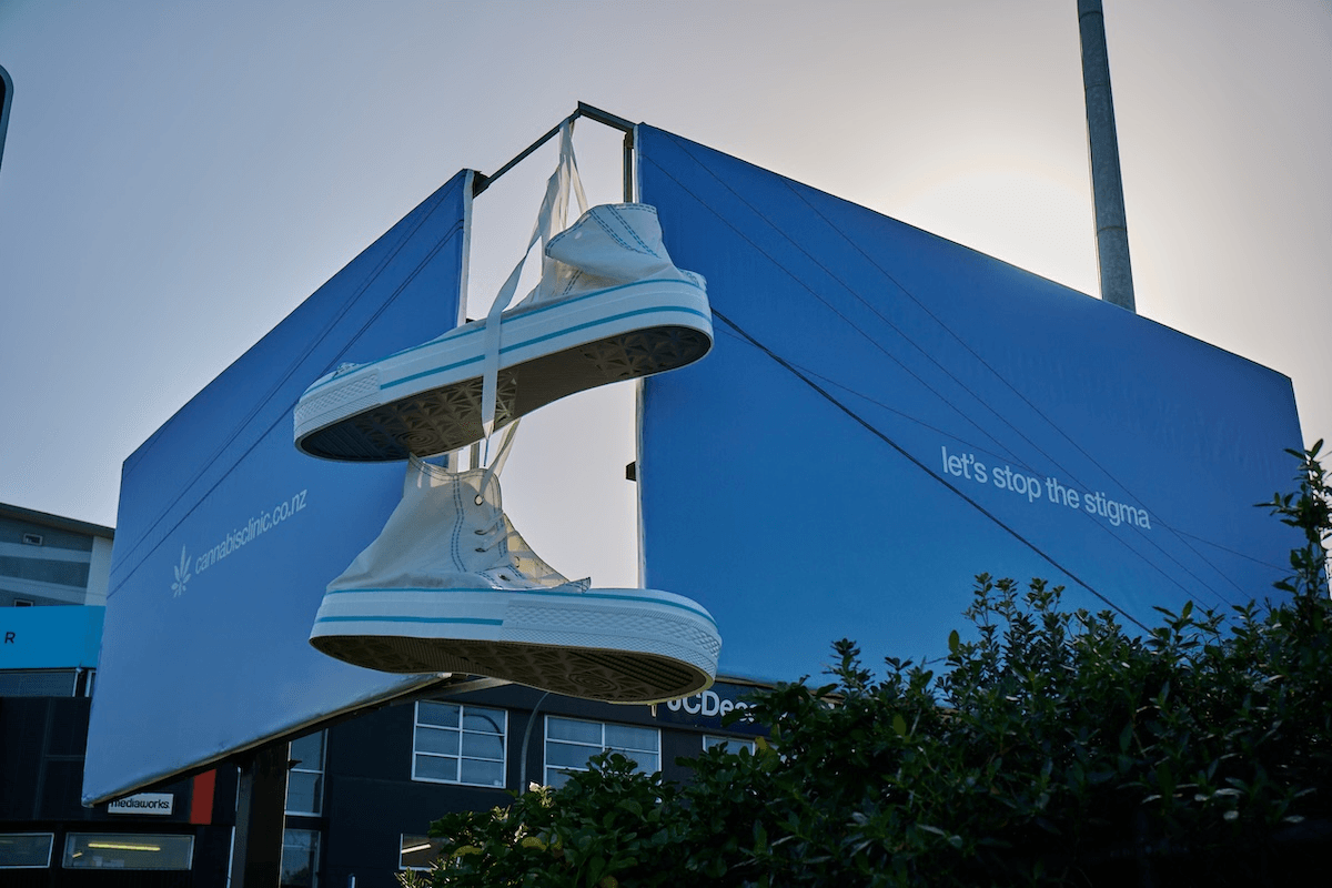 A pair of giant chuck taylor sneakers hang from two standalone billboards