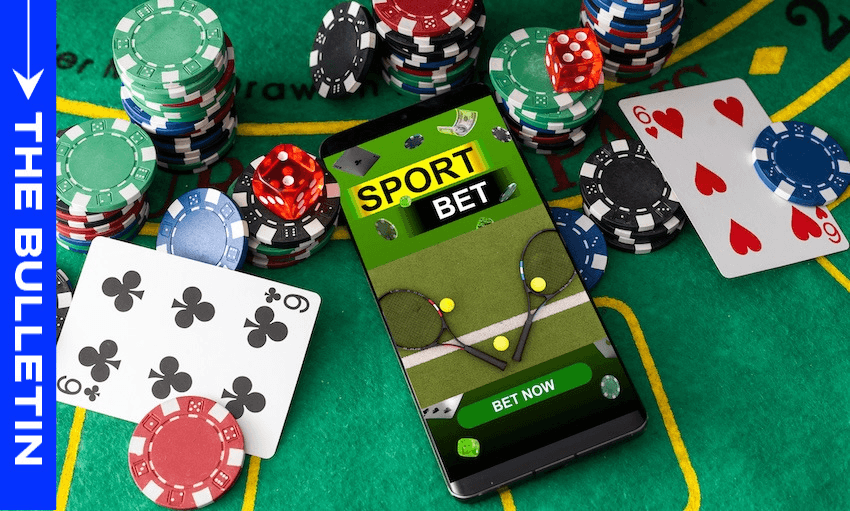 A smartphone displaying a sports betting app lies on a casino table surrounded by poker chips and playing cards. The left side features a blue banner with the text “THE BULLETIN.”.