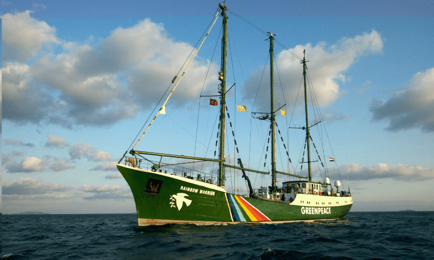 A photograph of the Greenpeace ship the Rainbow Warrior on the sea with a sunny blue sky with clumps of cloud above.
