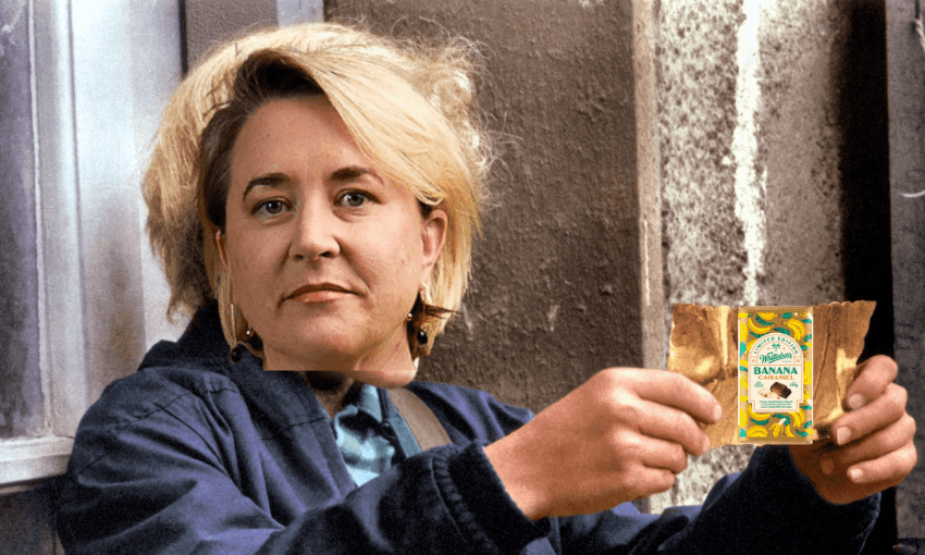 A person with short blond hair, wearing a dark jacket, sits outside holding a package of Barnana organic chewy banana bites. The background appears weathered and urban.