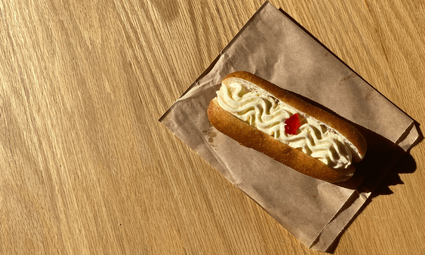 a cream donut with a red jam dot in the centre, on a wooden table