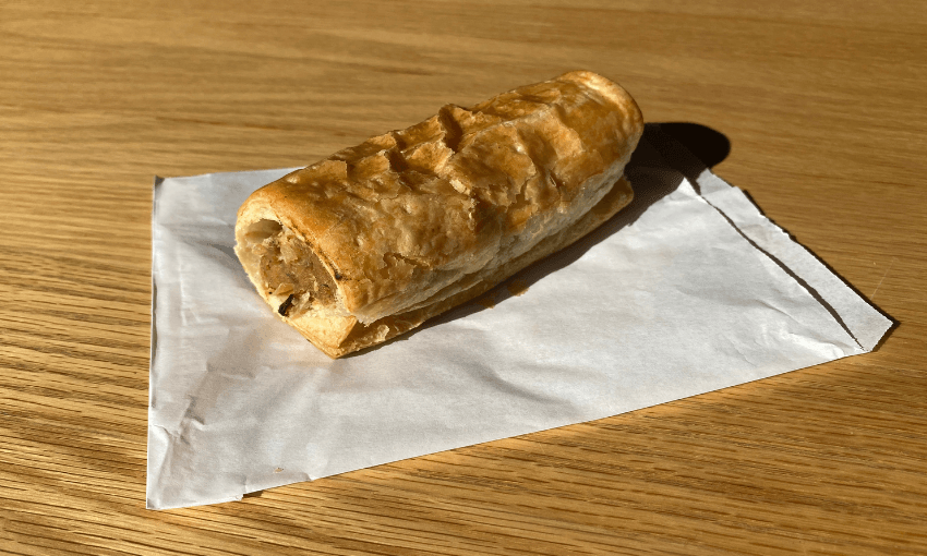 A sausage roll on a white paper bag on a table