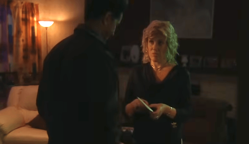 A blonde woman holds an envelope filled with money in a darkened lounge