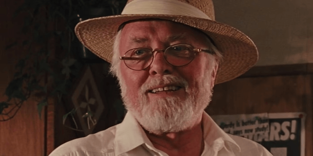 an older man with a white beard and round glasses, wearing a straw hat and a white collared shirt