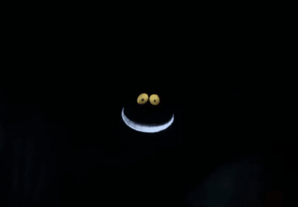 A black image with the cartoon glowing eyes and teeth of a cheshire cat