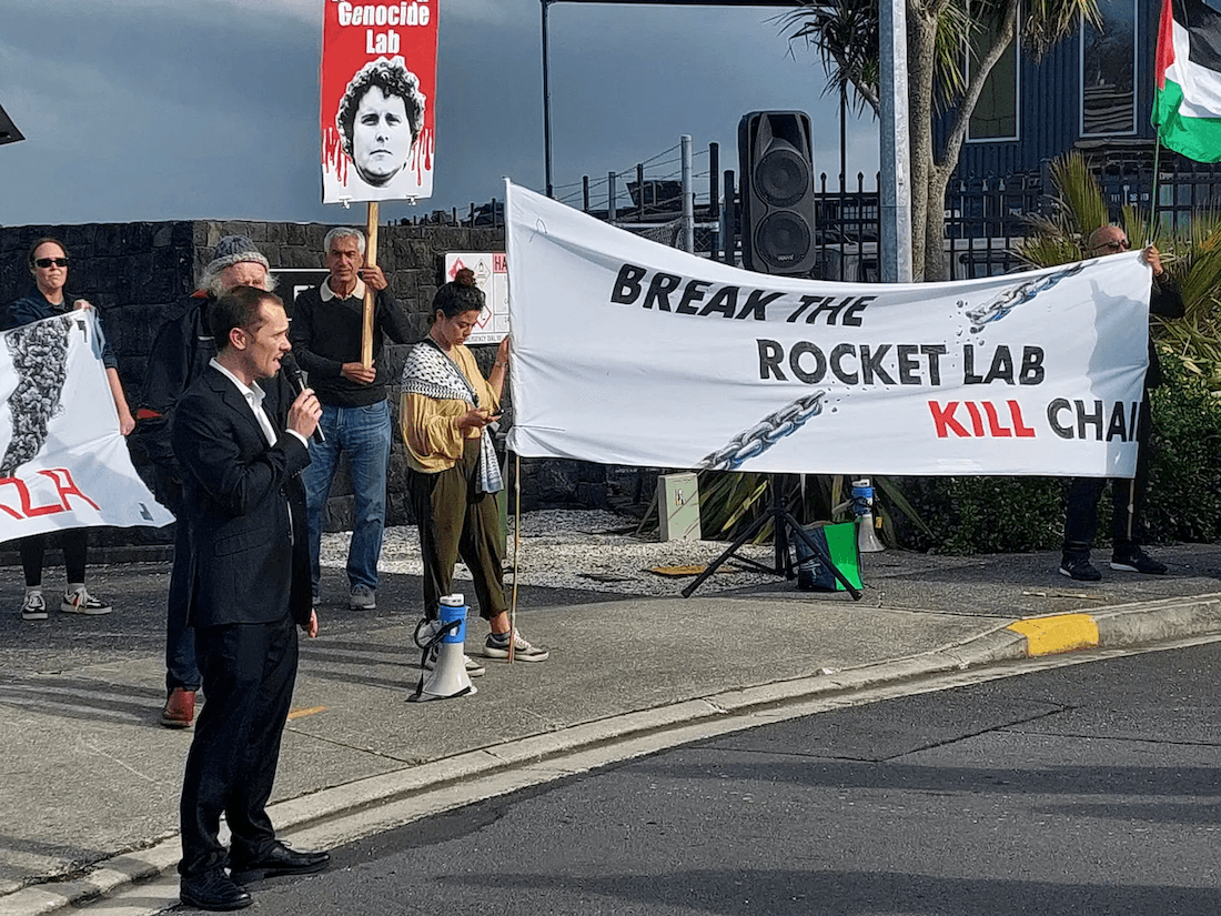 people holding hand painted signs one says 'break the rocket lab kill chain'