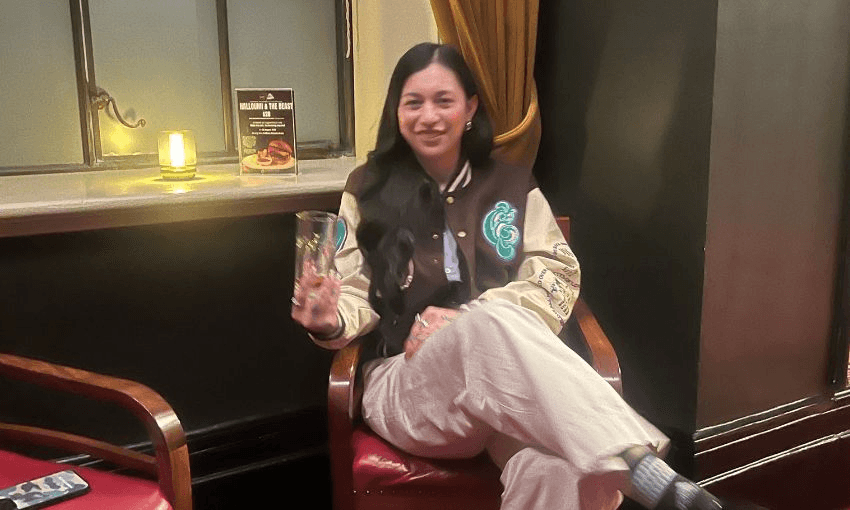 Green MP Tamatha Paul sits on a chair inside Pint of Order, smiling and holding a glass of coke.