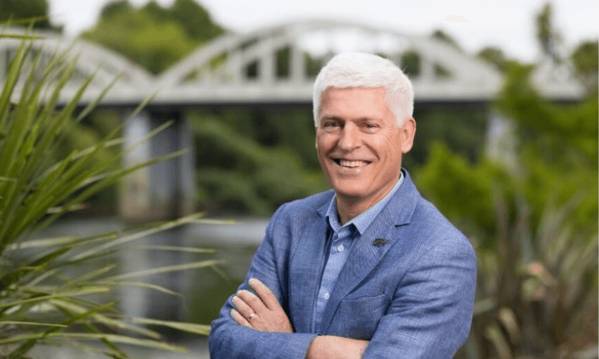 Headshot of Tim Macindoe with his arms folded over his chest.