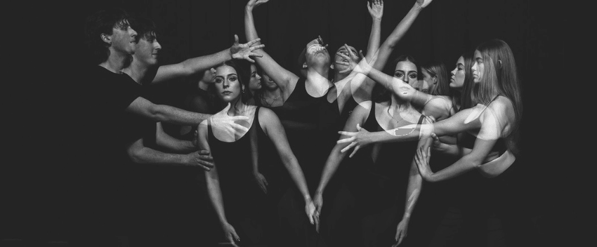 A photograph of dancers in a group making shapes with their hands. 
